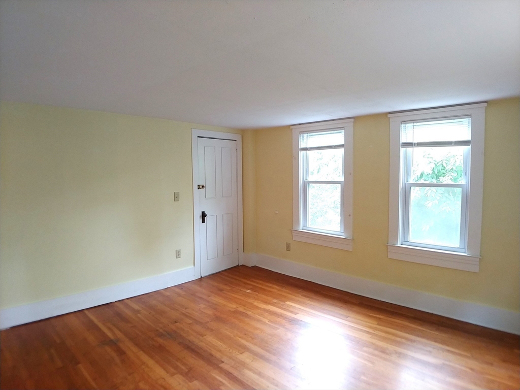 77 Hudson Street, Unit 2 Marlborough, MA 01752 - Photo 18 of 30 an empty room with wooden floor and windows