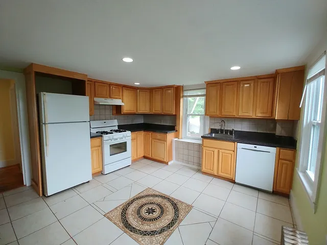 a kitchen with a refrigerator a stove top oven and cabinets