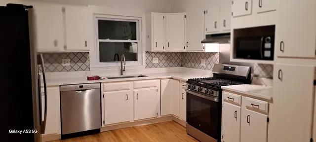 a kitchen with white cabinets and appliances