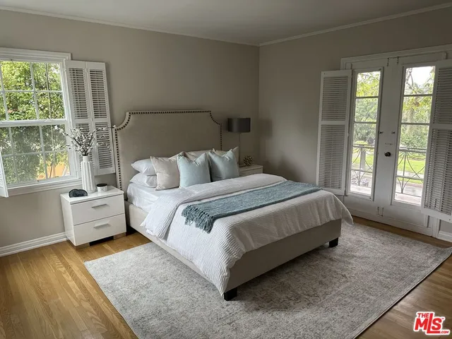 a bedroom with a bed and large windows