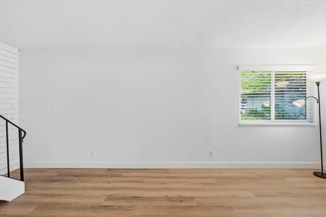 a view of an empty room with wooden floor and stairs