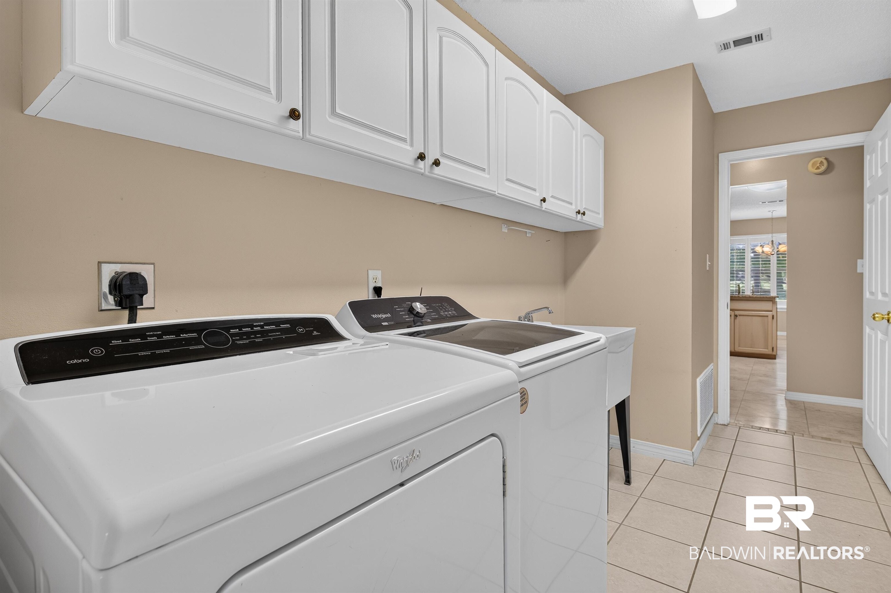 22685 County Road 12 Foley, AL 36535 - Photo 47 of 89 Dedicated laundry area featuring white upper cabinetry with dark hardware, a utility sink, and neutral tile flooring