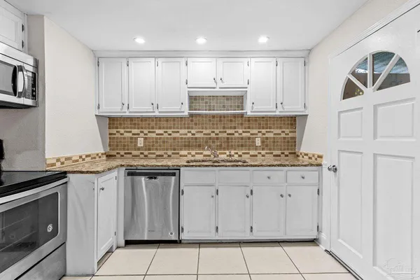 a kitchen with granite countertop white cabinets and stainless steel appliances
