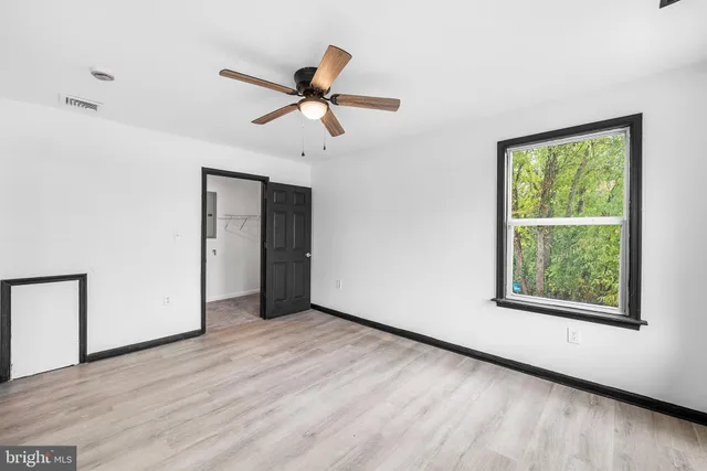 an empty room with windows and fan