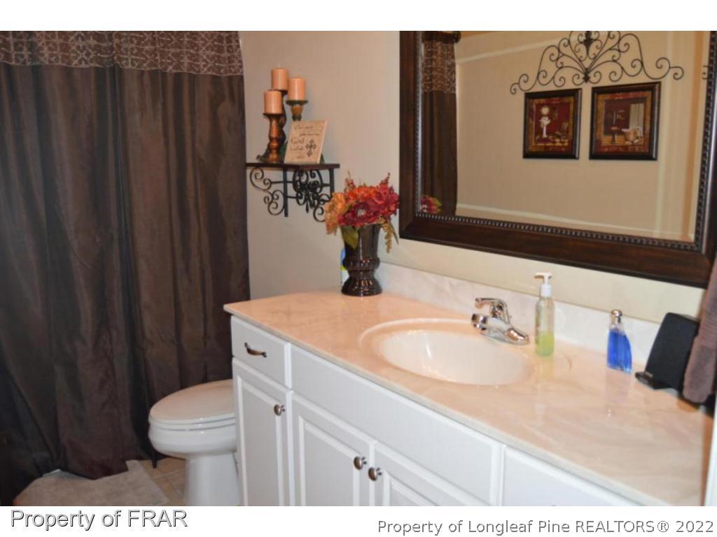 3940 Niagara Carthage Road Whispering Pines, NC 28327 - Photo 20 of 26 a bathroom with a sink vanity mirror and toilet