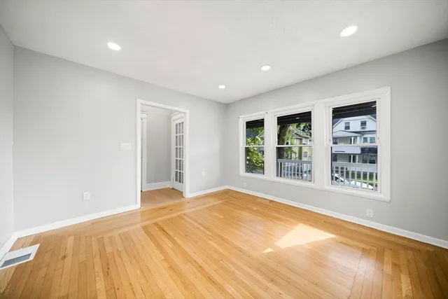 a view of an empty room with wooden floor and a window