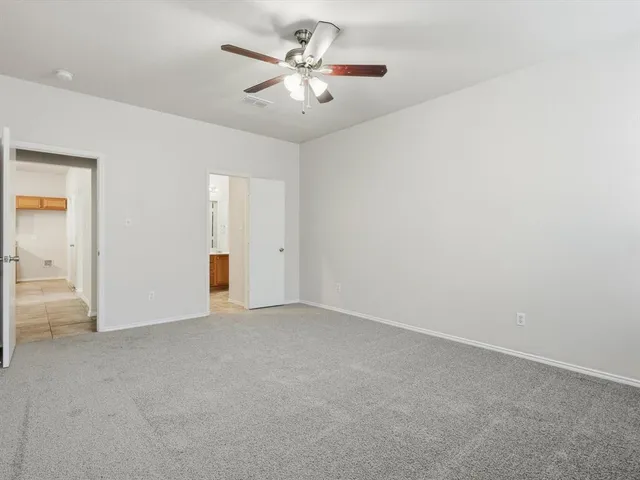 an empty room with chandelier fan and closet