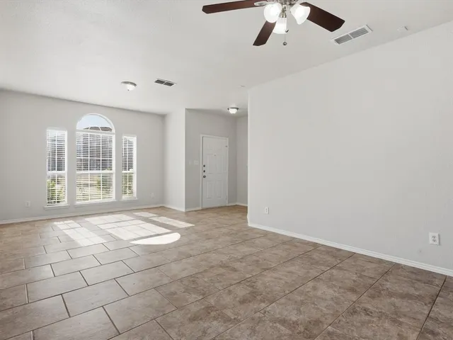 an empty room with windows and ceiling fan