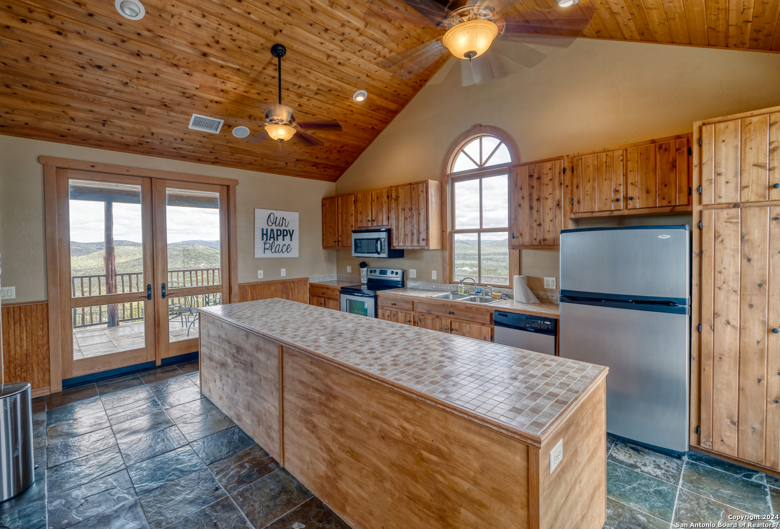 558 South Ridge Drive Concan, TX 78838 - Photo 17 of 35 a large kitchen with kitchen island granite countertop wooden cabinets a refrigerator and a large window