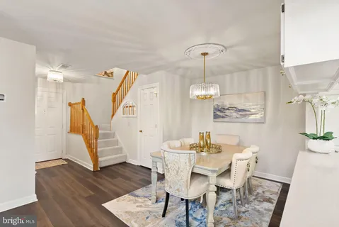 a dining room with wooden floor a chandelier a wooden table and chairs