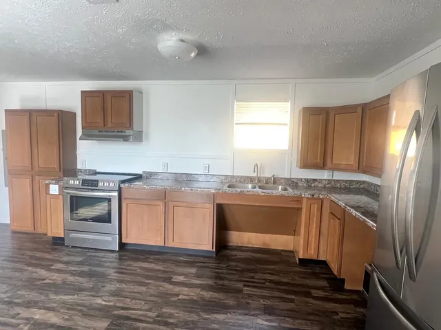 a kitchen with stainless steel appliances granite countertop a sink stove and refrigerator