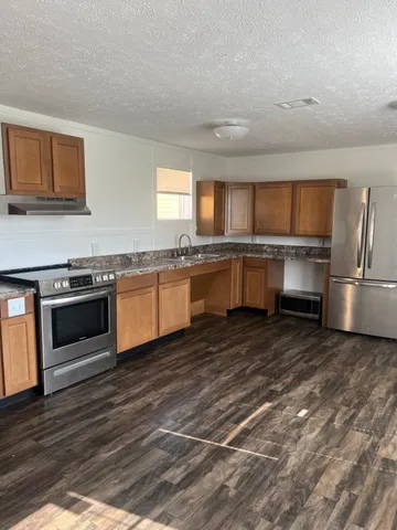 a kitchen with stainless steel appliances granite countertop a stove a sink and a microwave