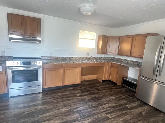 a kitchen with granite countertop a refrigerator and a sink