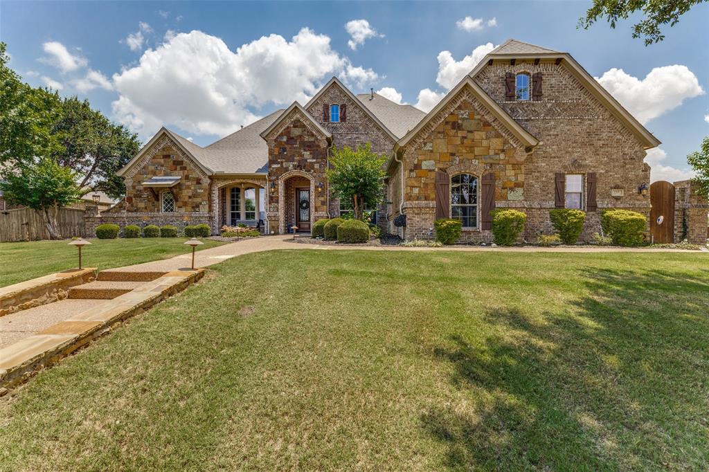 229 Arbor Lane Haslet, TX 76052 - Photo 2 of 34 Stone and brick exterior featuring multiple gables, arched entryways, dark wood shutters, a covered porch, and a stone walkway with integrated lighting