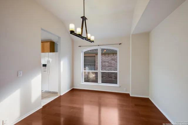 a view of empty room with wooden floor and window