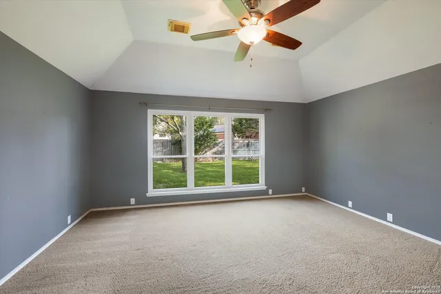 an empty room with windows and fan