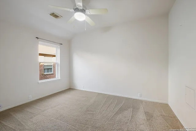 an empty room with a chandelier fan and windows