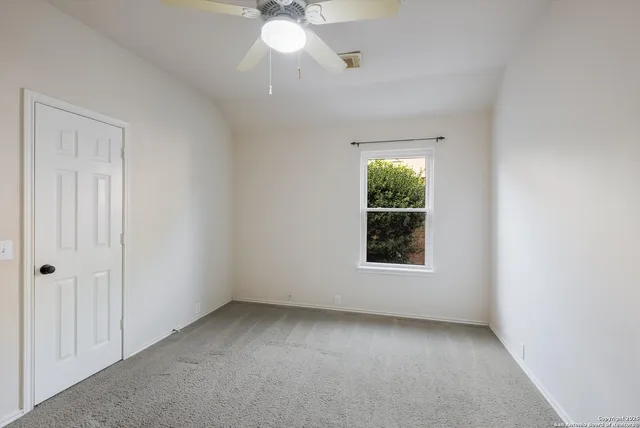 an empty room with a window and a chandelier fan