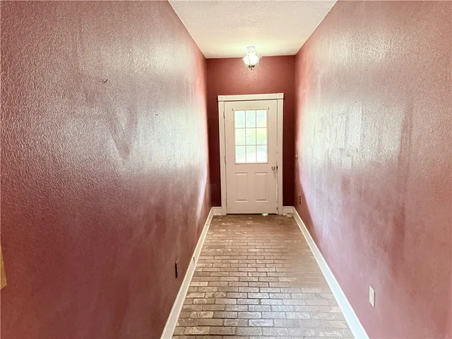 a view of an empty room with wooden floor and windows