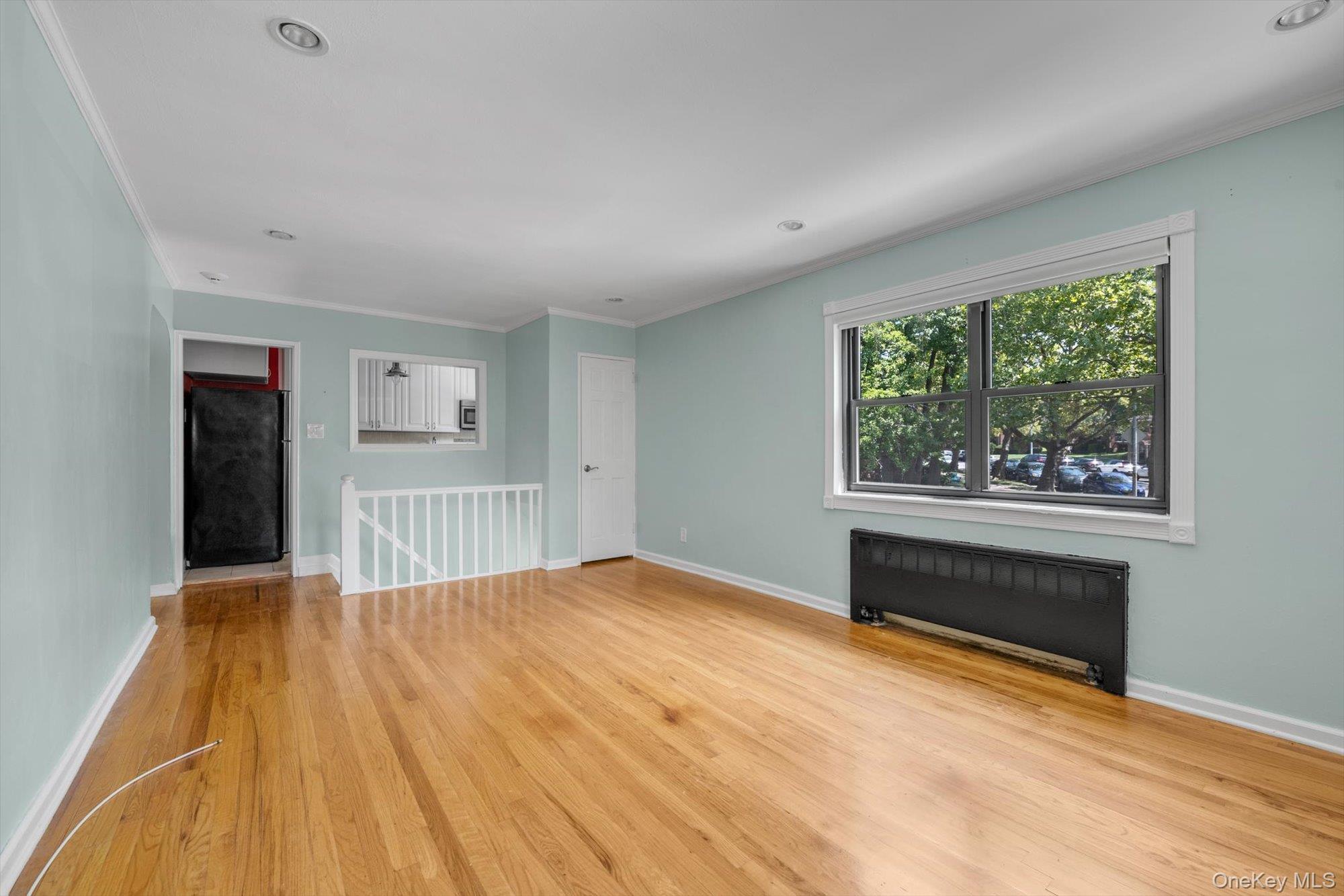 219-27 75th Avenue, Unit 2 Queens, NY 11364 - Photo 2 of 10 a view of an empty room with a window and wooden floor