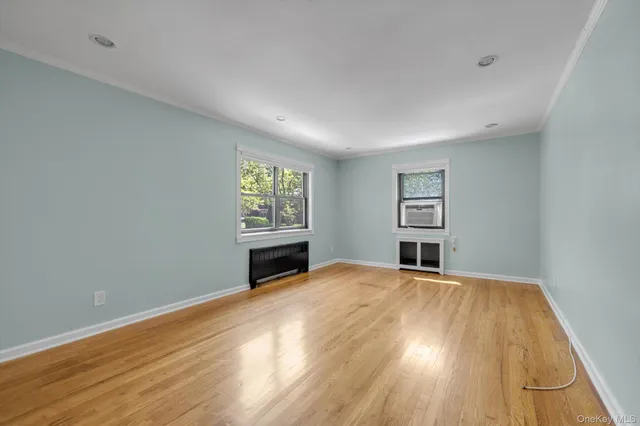 a view of an empty room with a window and wooden floor