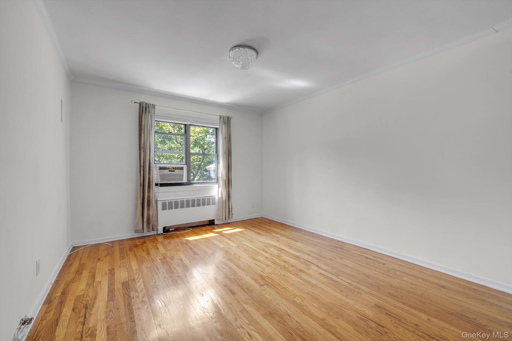219-27 75th Avenue, Unit 2 Queens, NY 11364 - Photo 6 of 10 a view of an empty room with wooden floor and a window