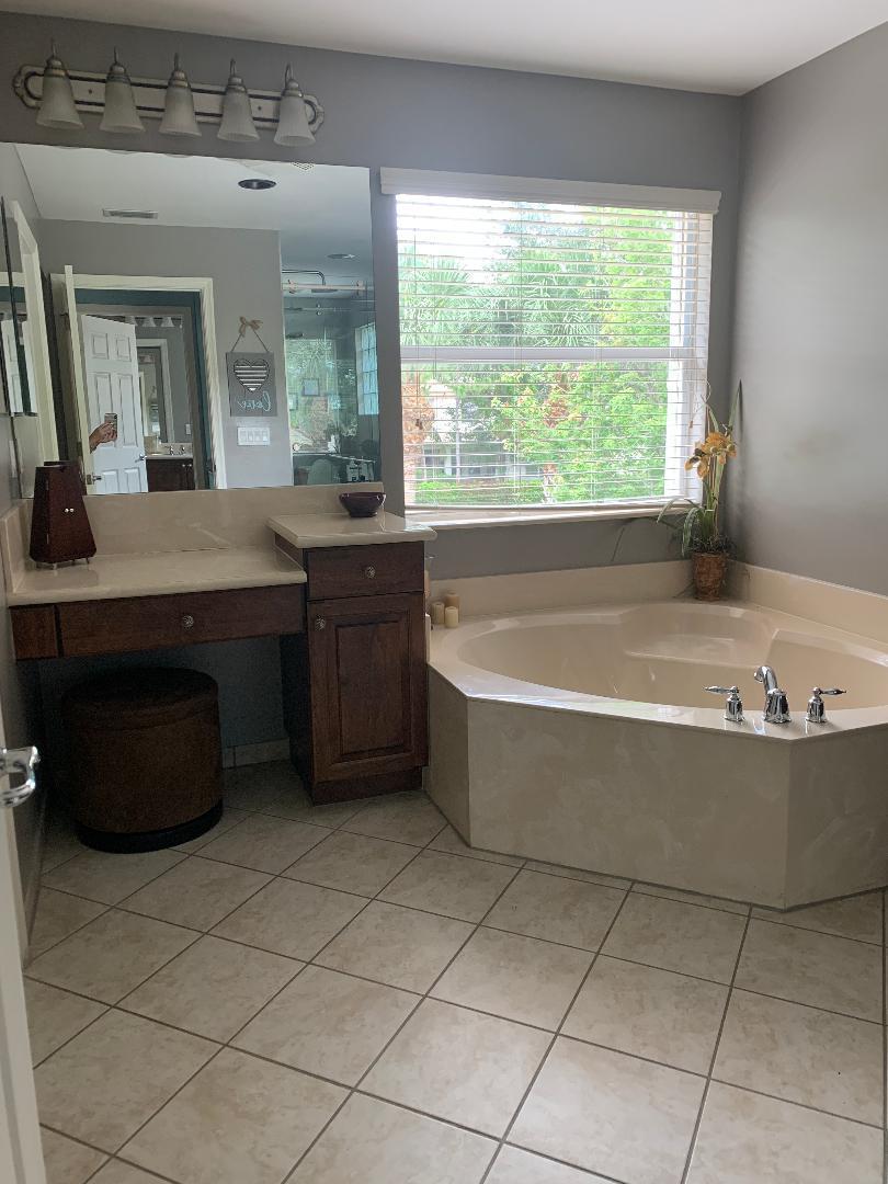 7907 Emerald Winds Circle Boynton Beach, FL 33473 - Photo 34 of 39 a bathroom with a tub a sink a mirror and a window