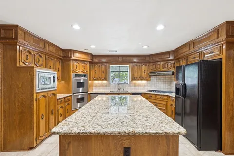 a kitchen with stainless steel appliances granite countertop counter top space stove refrigerator and wooden floor