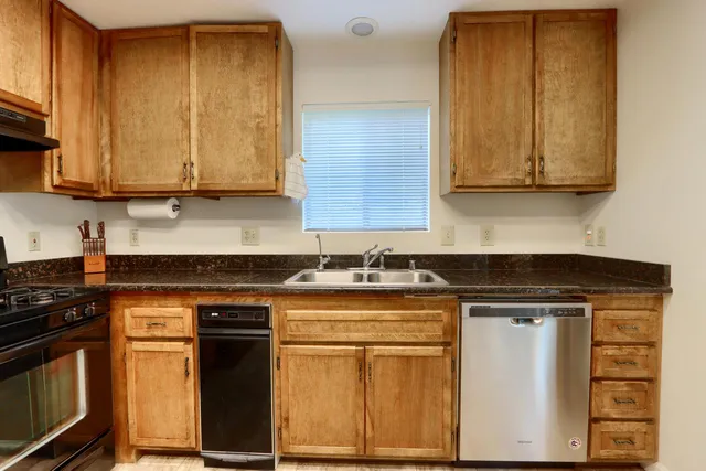 a kitchen with stainless steel appliances granite countertop a stove a sink and a microwave