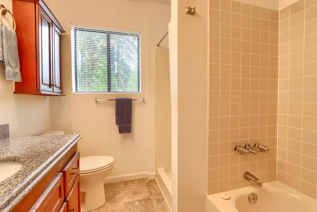 a bathroom with a granite countertop toilet a sink and a shower