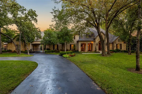 a front view of a house with a garden and trees