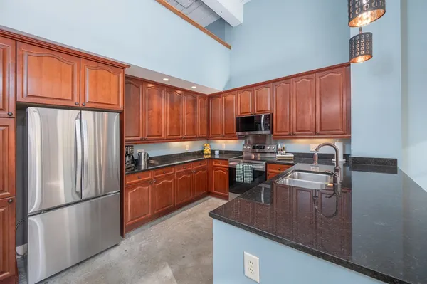 a kitchen with granite countertop wooden cabinets stainless steel appliances and a sink