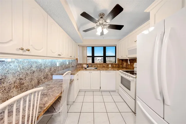 a kitchen with granite countertop white cabinets and white appliances