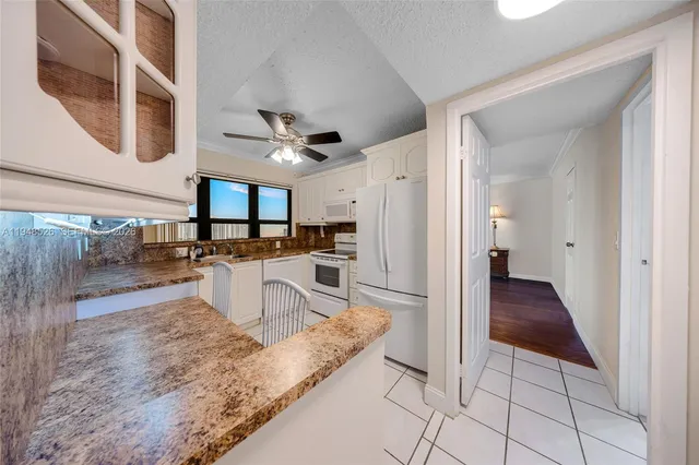 a kitchen with stainless steel appliances kitchen island granite countertop a refrigerator and a sink