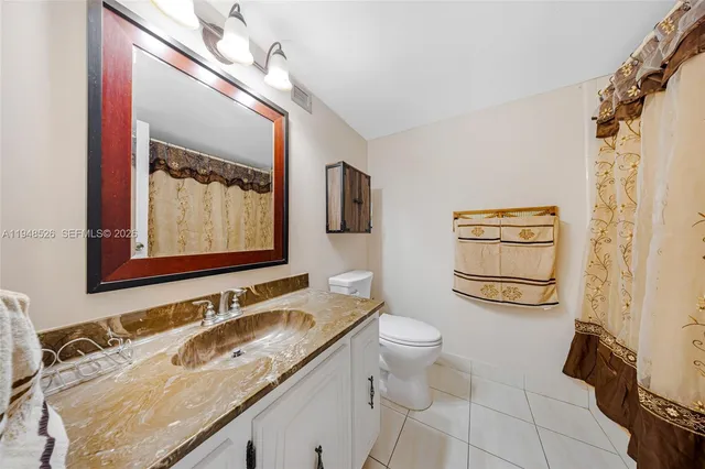 a bathroom with a granite countertop sink mirror vanity and toilet