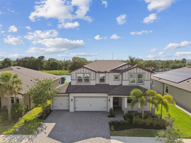 a view of a house with a big yard plants and large tree