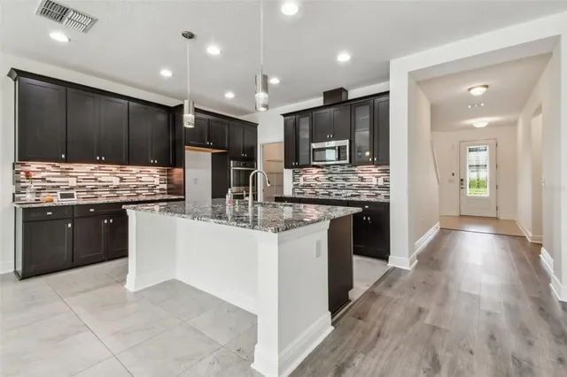 a kitchen with stainless steel appliances kitchen island granite countertop wooden cabinets a counter top space a sink and a stove