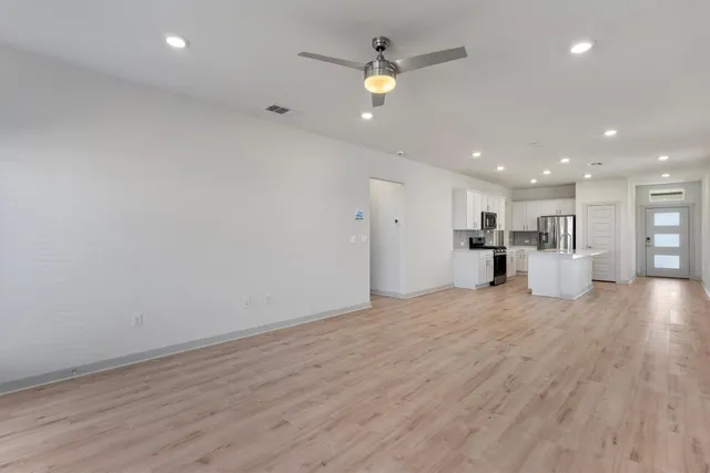 a view of an empty room with wooden floor and a window