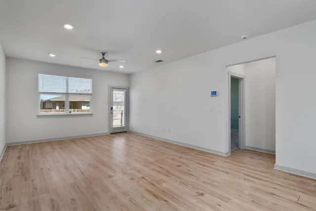 a view of empty room with wooden floor and windows