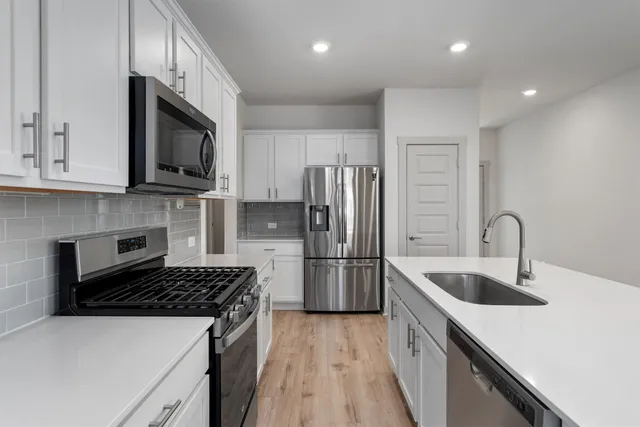 a large kitchen with a center island wooden floor stainless steel appliances and cabinets