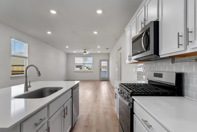 a kitchen with white cabinets and black appliances