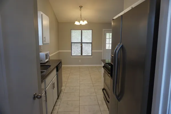 a bathroom with a granite countertop sink a refrigerator and a window