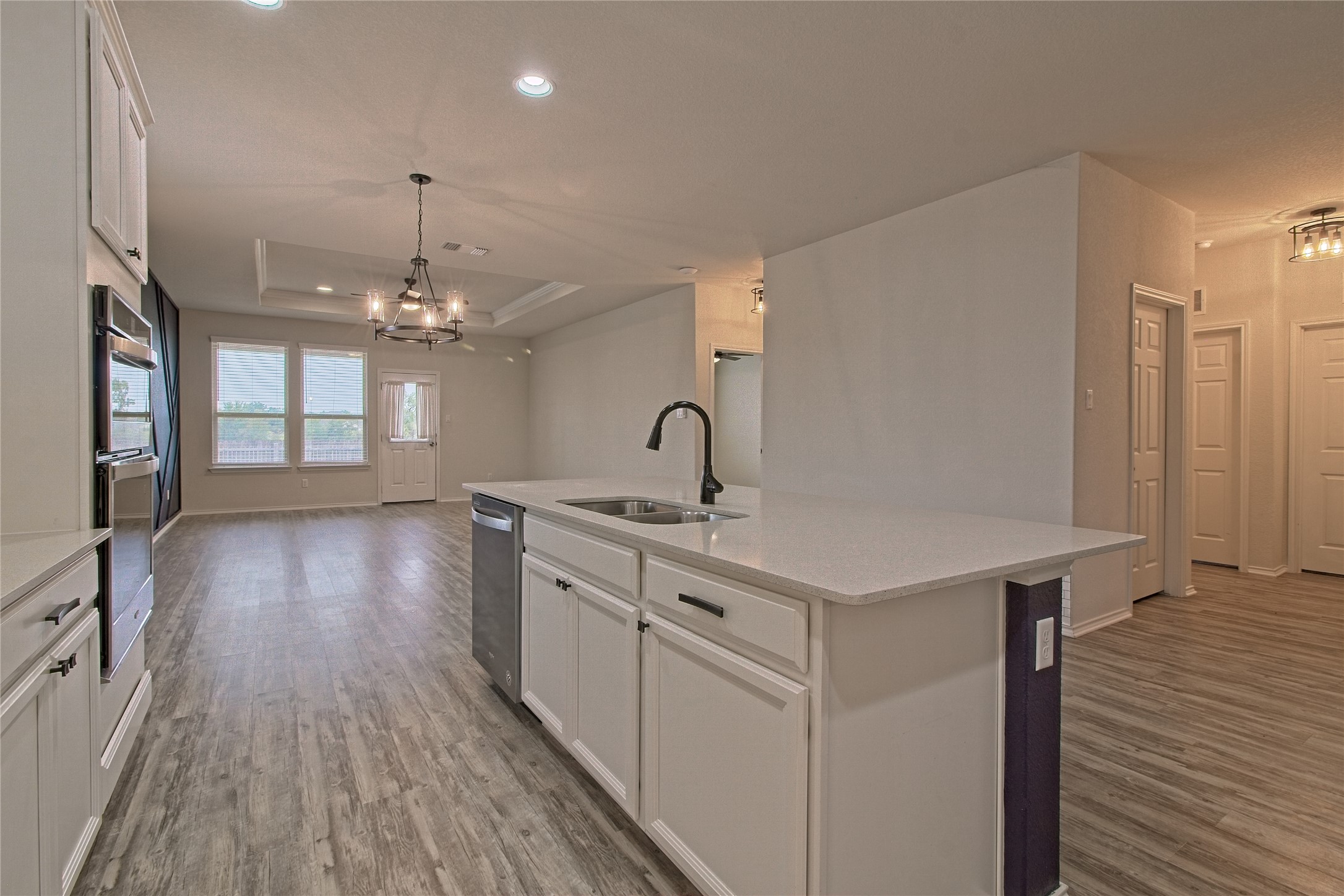 601 Hummingbird Lane Leander, TX 78641 - Photo 35 of 35 Kitchen with white cabinetry, an island with sink, a tray ceiling, open floor plan, and light wood finished floors