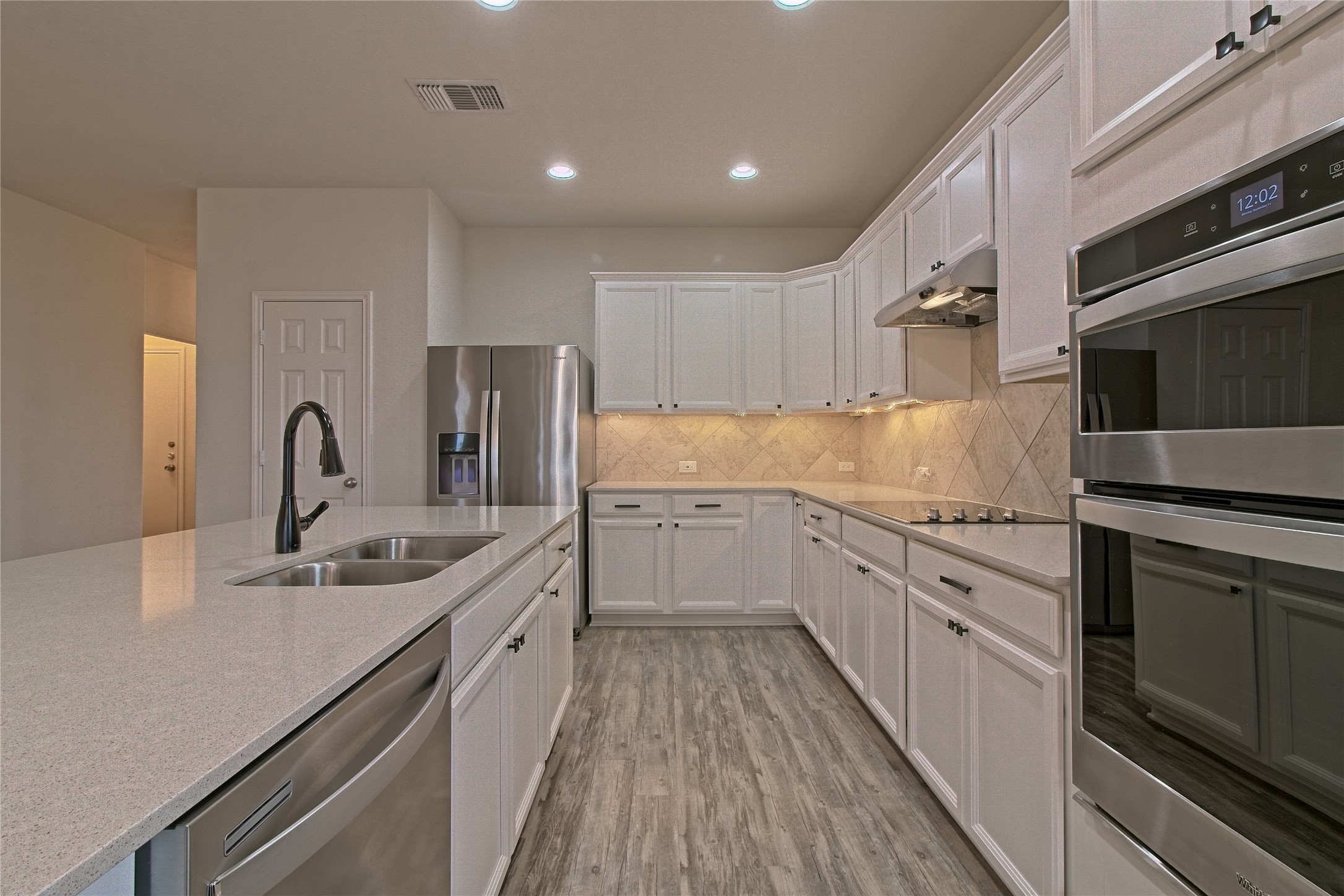 601 Hummingbird Lane Leander, TX 78641 - Photo 10 of 35 Kitchen featuring stainless steel appliances, white cabinets, light wood-style floors, recessed lighting, and backsplash