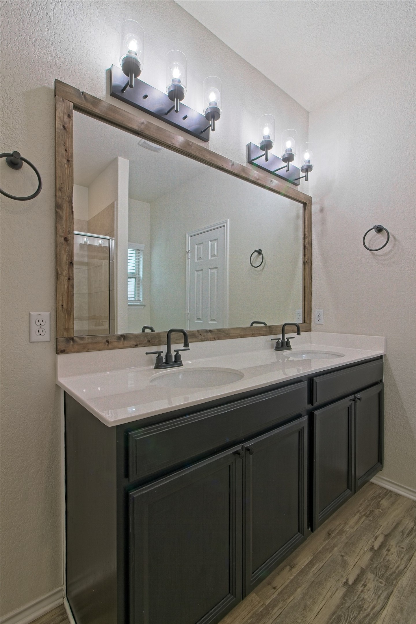 601 Hummingbird Lane Leander, TX 78641 - Photo 19 of 35 Full bathroom with a textured wall, double vanity, a shower stall, and light wood-type flooring