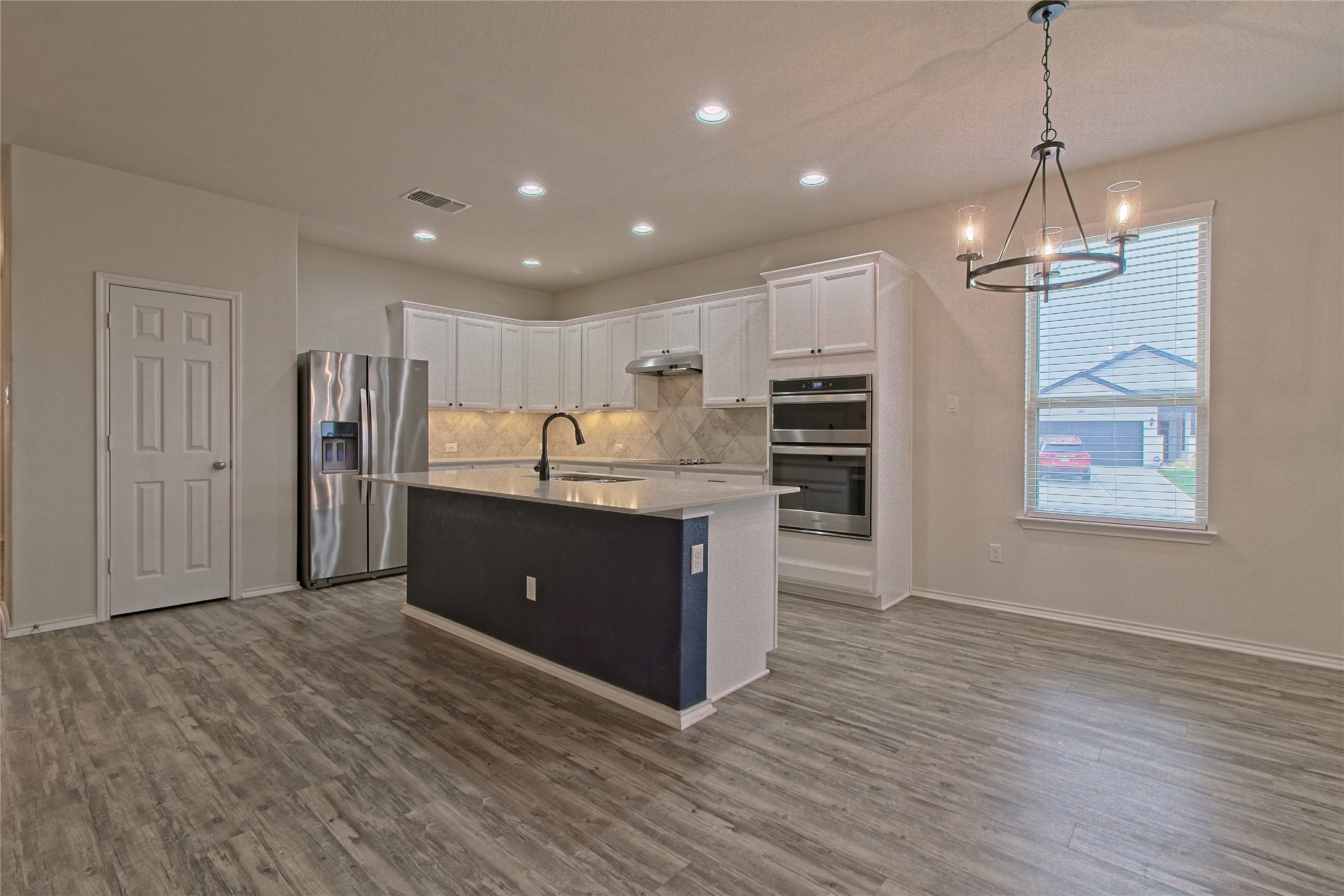 601 Hummingbird Lane Leander, TX 78641 - Photo 8 of 35 Kitchen featuring white cabinets, stainless steel appliances, a kitchen island with sink, decorative backsplash, and a chandelier
