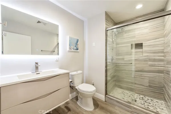a bathroom with a toilet a sink a mirror and shower