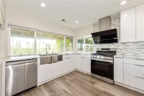 a kitchen with stainless steel appliances white cabinets and a stove top oven