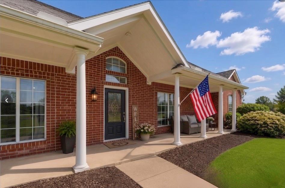 15 Trail Ridge Drive Melissa, TX 75454 - Photo 3 of 38 Brick exterior featuring a covered front porch with multiple columns, a decorative glass-paneled entry door, arched transom window, and a manicured lawn - virtually staged outdoor furniture