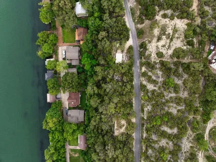 an aerial view of residential houses with outdoor space and trees all around